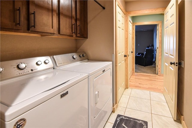 laundry room with light tile patterned floors, cabinet space, and separate washer and dryer