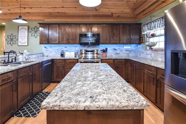 kitchen with light stone counters, backsplash, appliances with stainless steel finishes, a sink, and a kitchen island