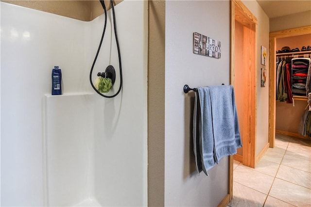 full bathroom featuring a shower, tile patterned flooring, a walk in closet, and baseboards