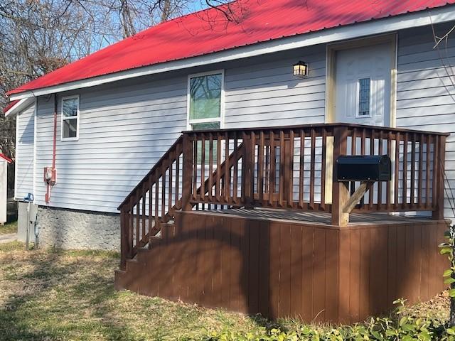 back of property with metal roof and a wooden deck