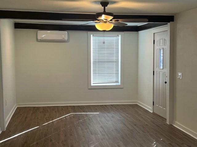 interior space with dark wood-style floors, a wall mounted air conditioner, baseboards, and a ceiling fan