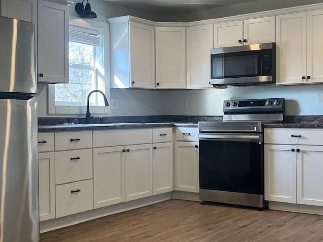 kitchen featuring stainless steel appliances, dark countertops, and white cabinetry