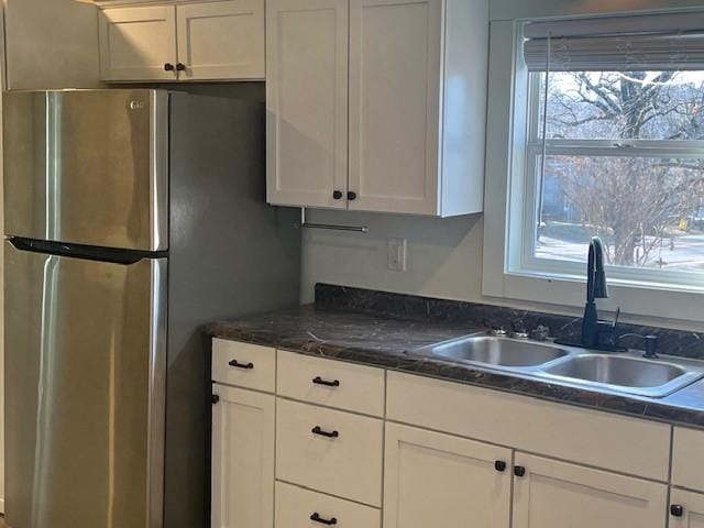 kitchen featuring white cabinets, a sink, and freestanding refrigerator