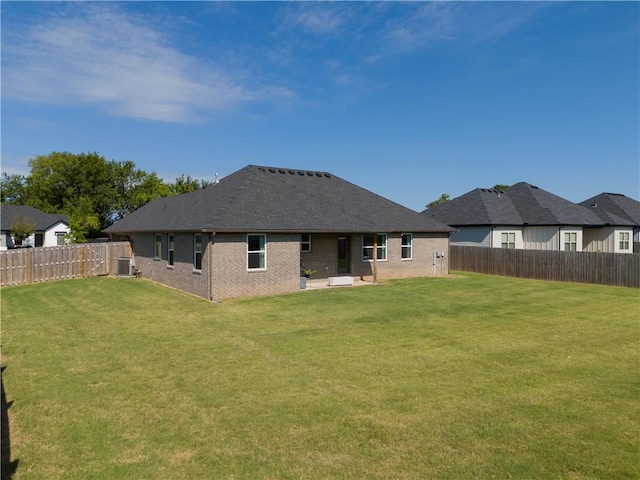 rear view of house featuring brick siding, a lawn, cooling unit, and a fenced backyard