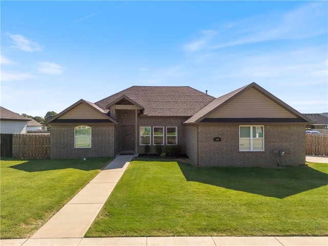 ranch-style house featuring a front yard, brick siding, and fence