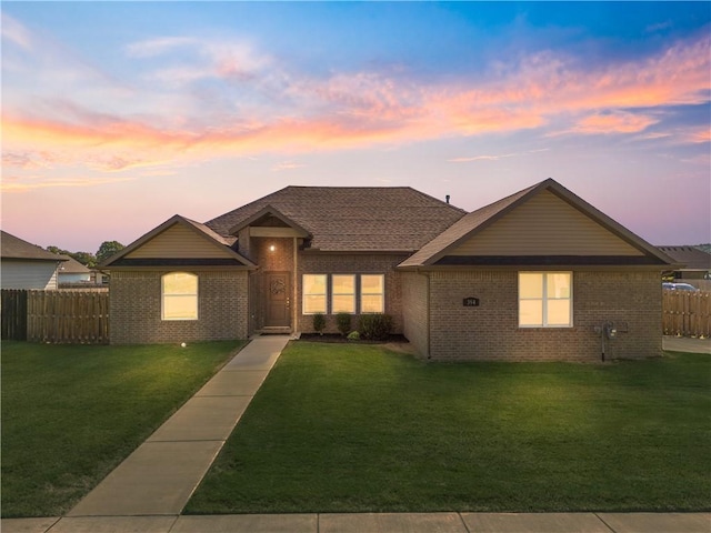 ranch-style house with brick siding, a lawn, and fence