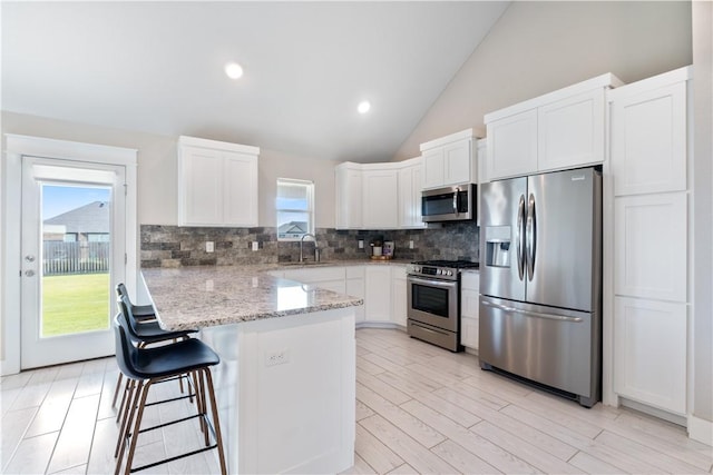 kitchen featuring stainless steel appliances, white cabinets, a peninsula, and a kitchen breakfast bar