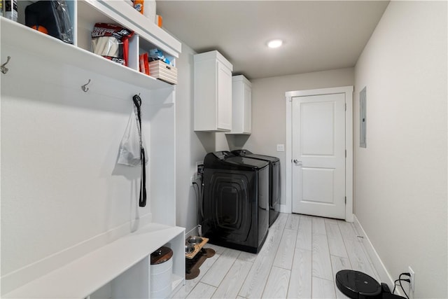 laundry area featuring light wood finished floors, independent washer and dryer, cabinet space, and baseboards