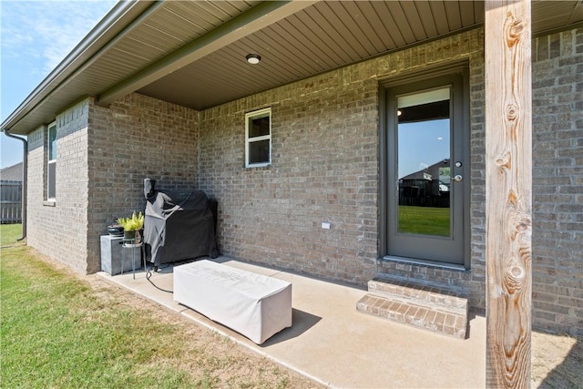 property entrance featuring brick siding and a patio