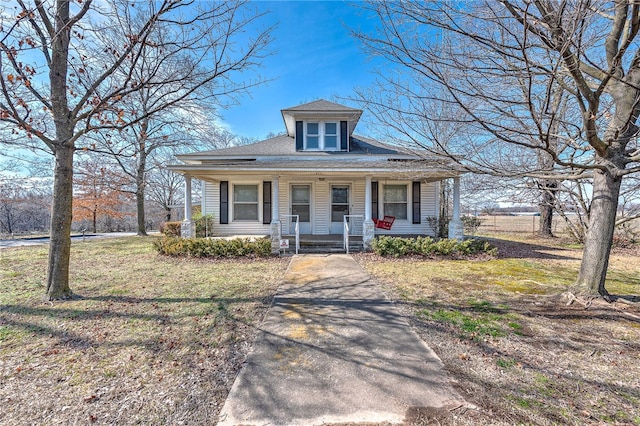 bungalow featuring covered porch and a front yard