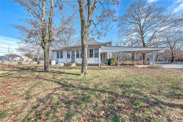 ranch-style house with entry steps, fence, a front lawn, and a detached carport