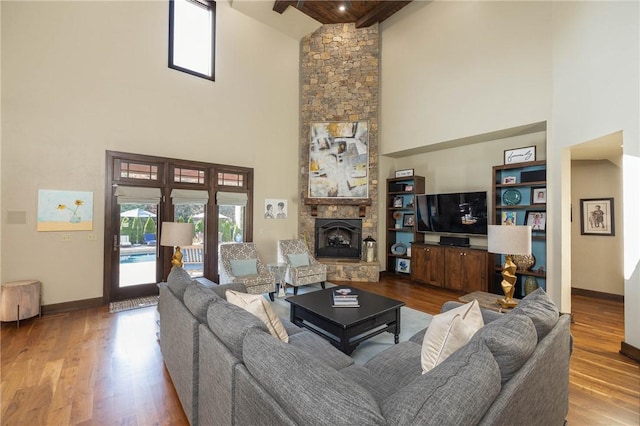 living area with baseboards, wood finished floors, and a stone fireplace