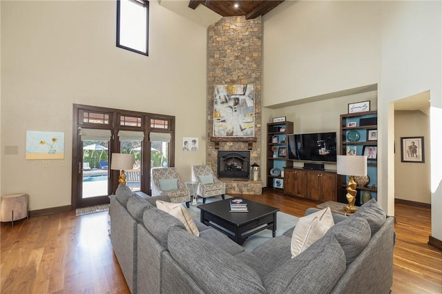 living area with wood finished floors, a fireplace, baseboards, and a towering ceiling
