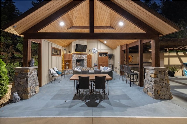 view of patio / terrace with exterior bar, an outdoor stone fireplace, and a gazebo