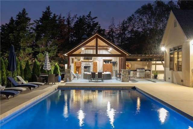 pool with exterior kitchen, a patio area, exterior fireplace, and grilling area