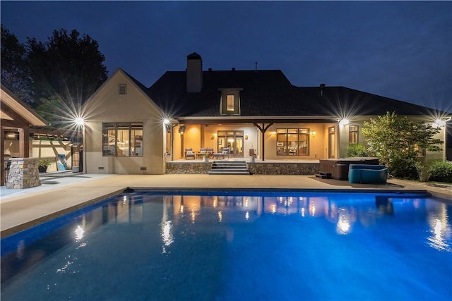 pool at night featuring a patio area and an outdoor pool