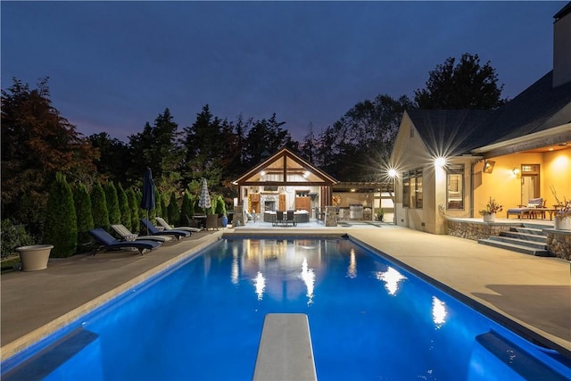 outdoor pool with a patio area, an outbuilding, a diving board, and an exterior structure