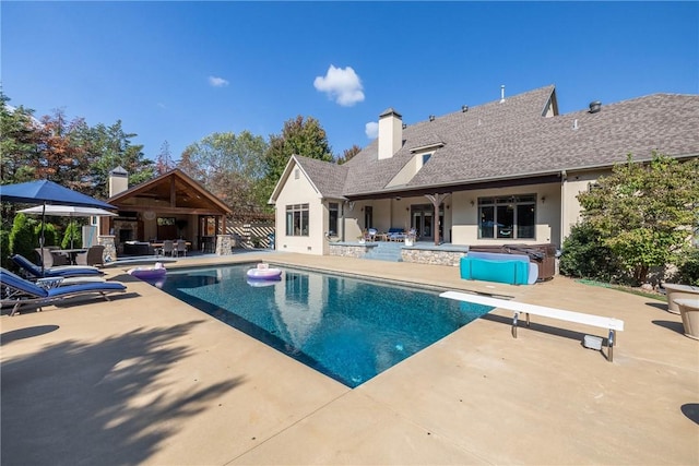 outdoor pool with a diving board, a patio, fence, and a hot tub