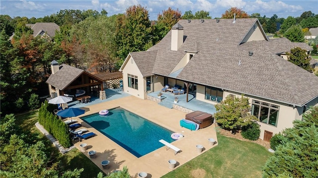 outdoor pool with a yard, a hot tub, an outdoor hangout area, a patio area, and a bar