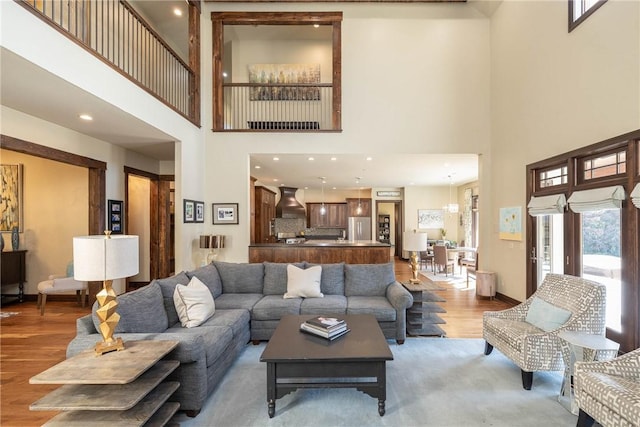 living area featuring a high ceiling, light wood-type flooring, recessed lighting, and baseboards