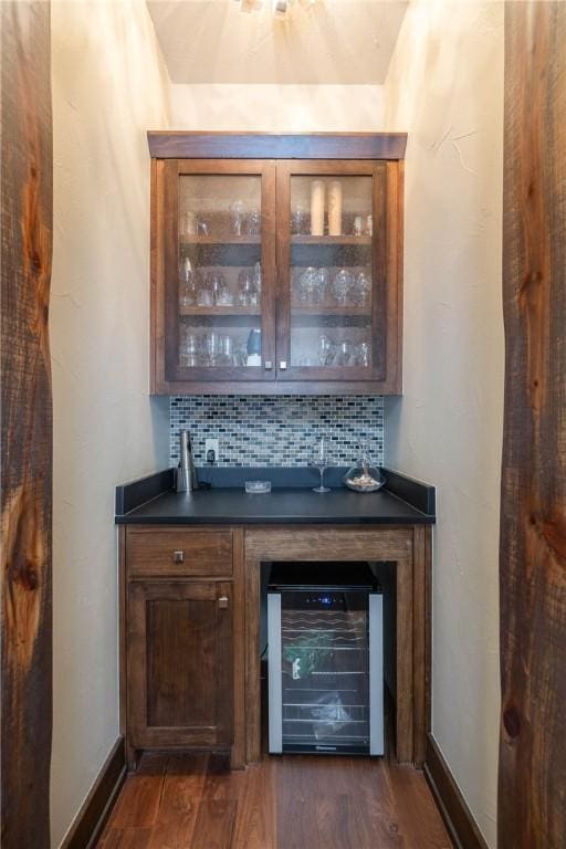 bar with beverage cooler, baseboards, backsplash, a dry bar, and dark wood finished floors