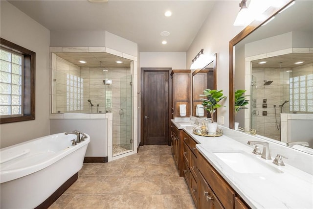 full bathroom featuring a shower stall, double vanity, a sink, and a soaking tub