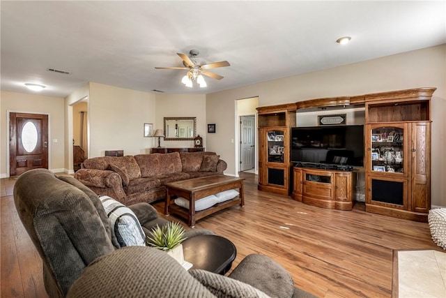 living area featuring baseboards, light wood-style flooring, and a ceiling fan