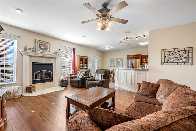 living area featuring light wood-type flooring, ceiling fan, and a tile fireplace