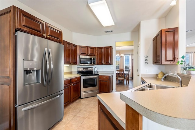 kitchen featuring visible vents, appliances with stainless steel finishes, an inviting chandelier, light countertops, and a sink