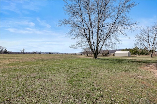 view of yard with a storage unit, an outbuilding, and a rural view