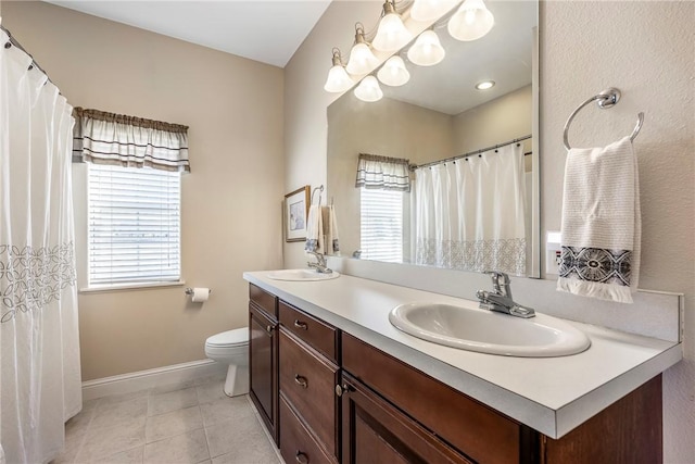 bathroom featuring double vanity, tile patterned flooring, a sink, and toilet