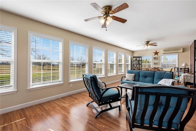 living area with a ceiling fan, a healthy amount of sunlight, baseboards, and wood finished floors