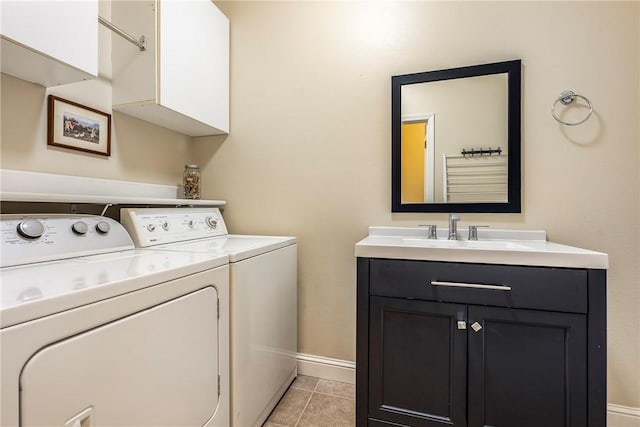 washroom with light tile patterned floors, separate washer and dryer, a sink, baseboards, and cabinet space