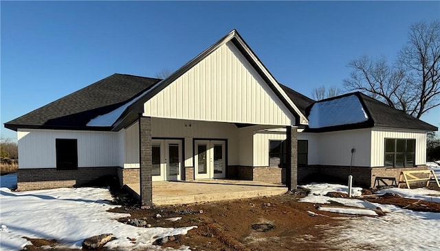 snow covered rear of property with a patio and french doors