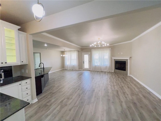 unfurnished living room with a chandelier, ornamental molding, a fireplace, and light wood-style floors