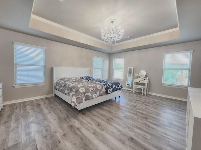 bedroom featuring a tray ceiling, baseboards, an inviting chandelier, and wood finished floors