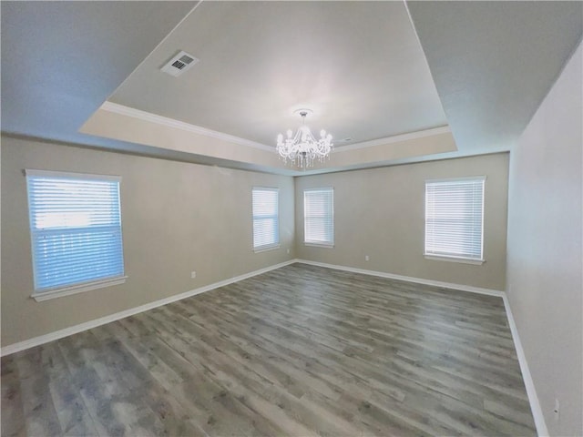 unfurnished room featuring a chandelier, a raised ceiling, visible vents, and wood finished floors