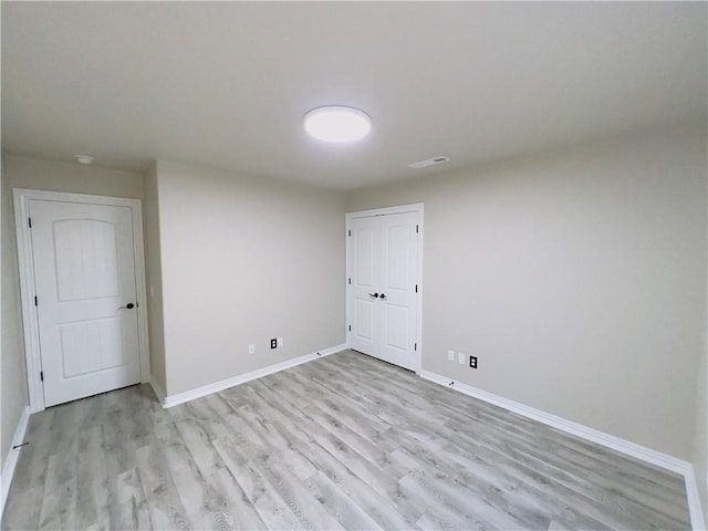 spare room with light wood-style floors, visible vents, and baseboards