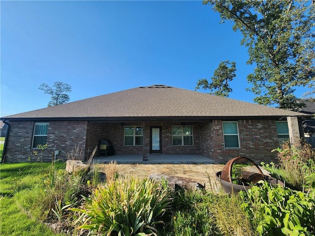 rear view of house with a patio, brick siding, and roof with shingles