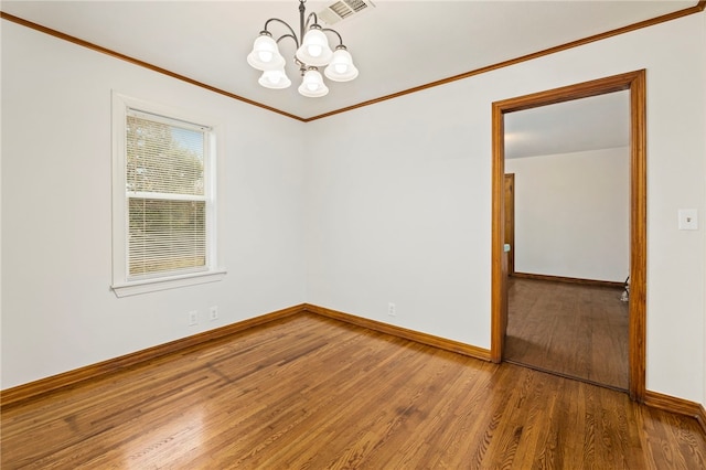 spare room featuring ornamental molding, wood finished floors, visible vents, and baseboards