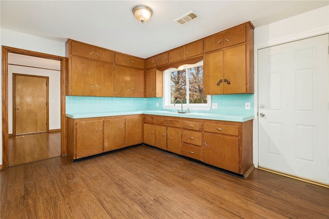 kitchen featuring brown cabinets, light countertops, visible vents, a sink, and wood finished floors