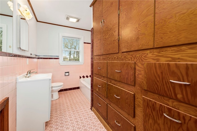 full bathroom with toilet, visible vents, vanity, tile walls, and ornamental molding