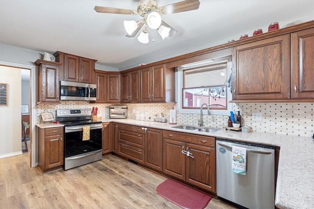 kitchen with light countertops, appliances with stainless steel finishes, a sink, and light wood-style floors