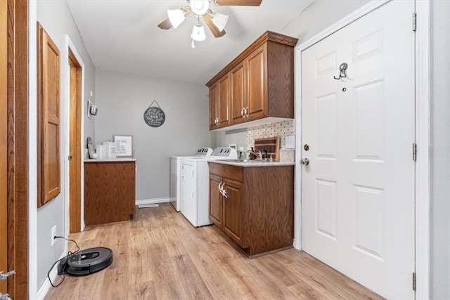 washroom featuring a ceiling fan, baseboards, independent washer and dryer, cabinet space, and light wood finished floors