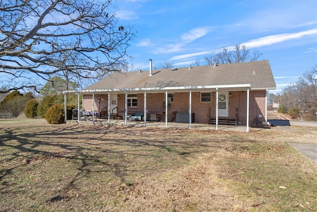 rear view of property featuring entry steps, a yard, brick siding, and a patio area