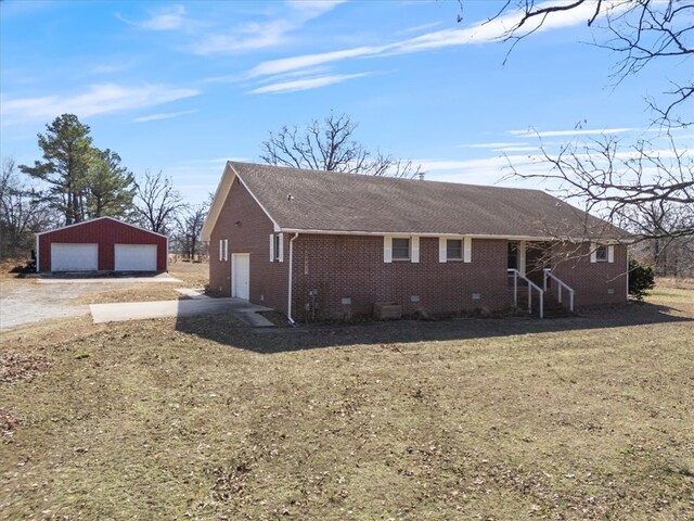 view of front facade with an outbuilding, brick siding, a detached garage, driveway, and crawl space