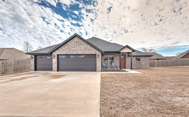 view of front facade with a garage, driveway, fence, and brick siding