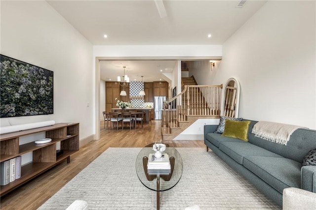 living area with light wood finished floors, baseboards, stairway, a notable chandelier, and recessed lighting