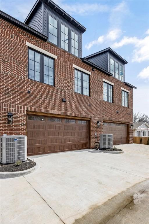 445 NW C St, Bentonville, AR 72712 - view of side of property with a garage, concrete driveway, and brick siding