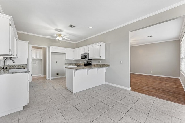 kitchen featuring a peninsula, stone countertops, stainless steel appliances, and a sink